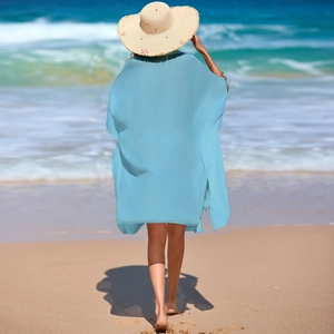 Back view of a light blue loose-fit beach cover-up on a sandy seashore landscape