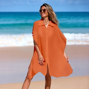 Detail of loose orange polo beach cover-up featuring button closure and high side slits
