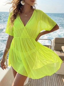Detail of neon green mesh beach cover-up with deep V-neck and cinched waist on a yacht
