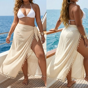 Detail of white halter bikini top paired with a beige tassel sarong skirt on a boat