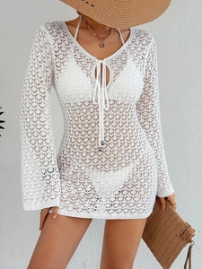 Détail de la tunique de plage en crochet blanc avec col en V et cordons à glands