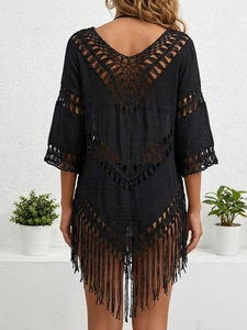 Détail d'un cardigan noir au crochet avec motifs ajourés complexes et longues franges bohèmes