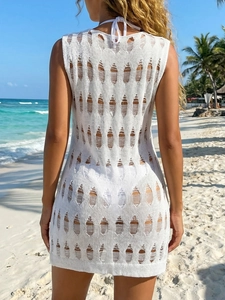 Detail of white crochet beach cover-up with geometric hollow knit pattern and fringe trim