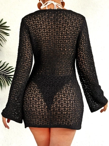 Détail d'une robe de plage en crochet noir avec motifs ajourés et lacets blancs