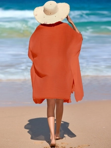 Bright orange loose beach cover-up with polo collar and batwing sleeves in seaside setting