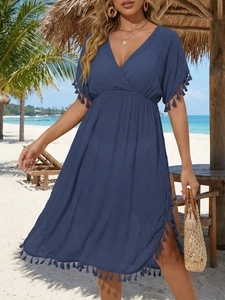 Detail of dark blue beach cover-up with V-neckline, waist pleats, and boho tassel trim