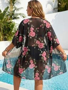 Outdoor back view of a loose black floral mesh beach cover-up with rose print