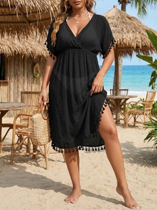 Detail of black beach cover-up featuring V-neckline and tassel trim on the hem and sleeves