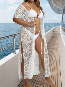 Elegant white lace bikini cover-up with pom-pom trim and side slits on a yacht deck