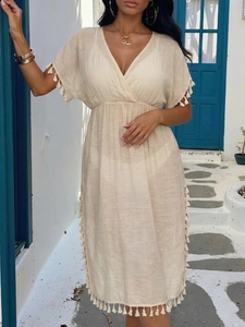 Detail of V-neck beach cover-up featuring cream linen fabric and elegant tassel fringe