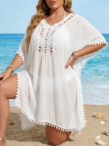 Détail d'un cache-maillot de plage blanc bohème avec dentelle crochet et pompons blancs