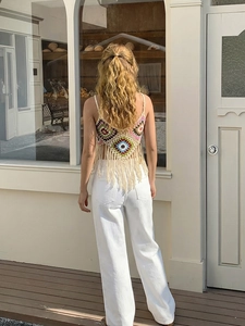 Detailansicht der Rückseite eines bunten, handgehäkelten Crop-Tops mit Boho-Fransenbesatz