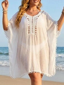 Détail du col en crochet et des pompons blancs sur la robe de plage ajourée