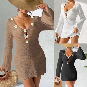 Detail of crochet beach cover-up with bell sleeves and white floral V-neck accents