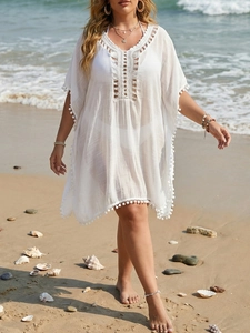 Détail de la tunique de plage blanche avec décolleté au crochet et bordure à pompons