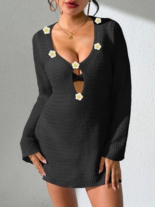 Detail of crochet daisy flowers on deep V-neck of a black knit mini beach dress