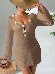 Detail of crochet beach coverup featuring white flower appliques on deep V-neckline