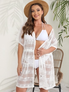 Detailed macro view of white crochet lace beach cover-up with drawstring waist and knit texture
