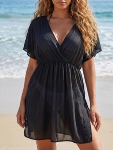 Detail of sheer black beach cover-up with deep V-neck and high side slits on sandy beach