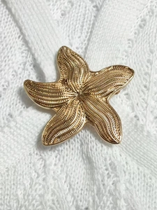 Macro shot of detailed gold starfish metal accessory on a white lace fabric background