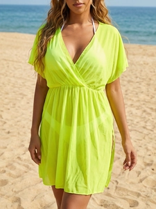 Detail of neon yellow mesh beach cover-up featuring a deep V-neck and high waistline