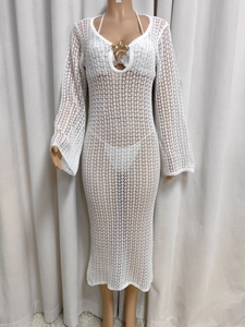 Detailed view of deep V-neckline with golden starfish charm on white crochet beach dress