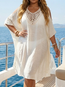 Detail of white crochet knit beach cover-up featuring intricate hollow out V-neck patterns