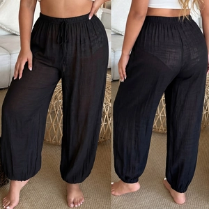 Dettaglio dei pantaloni da spiaggia neri trasparenti con coulisse e polsini stile jogger