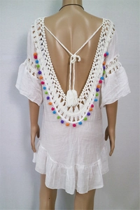 Detail of bohemian white beach coverup with crochet edges and colorful pompoms on the back