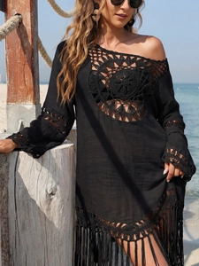 Détail d'une robe de plage noire au crochet avec motifs ajourés et longues franges