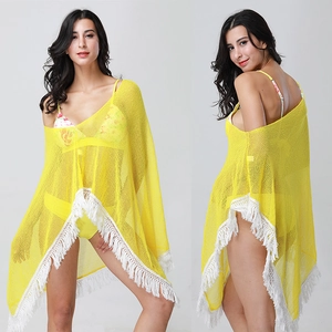 Close-up of yellow crochet beach shawl with hollow flower lace and white tassel fringe