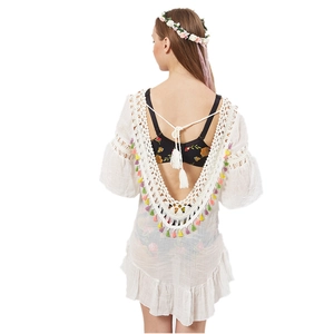 Close-up of white crochet beach cover-up with colorful tassels and lace detailing