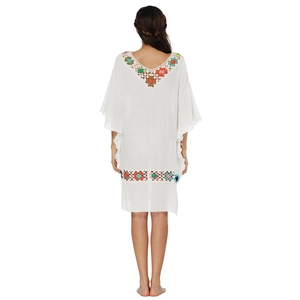 Détail de fleurs au crochet sur robe de plage blanche dos nu avec manches à volants
