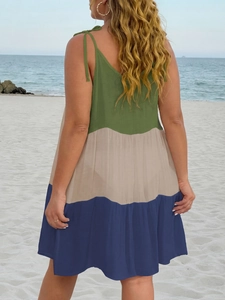 Detail of bohemian patchwork maxi dress with shoulder ties on a sunny beach background