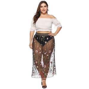 Détail de broderies florales colorées sur jupe en tulle noir avec taille élastique rayée