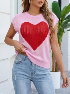 Detail view of a pink knit vest featuring a large red heart jacquard and crew neck