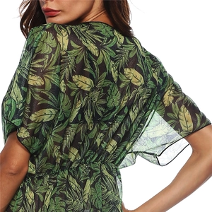 Detail of tropical palm leaf print on sheer mesh fabric with shimmering gold thread finish