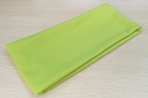 Close-up of fluorescent green elastic knitted headband stacked on light wood surface
