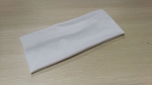 Flat lay of a plain white elastic sport headband on a light wood background