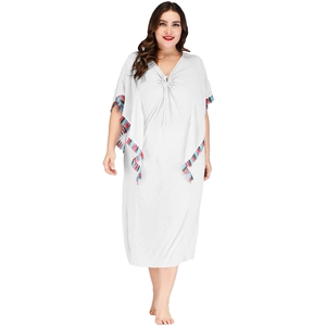Détail d'une robe longue caftan bohème blanche avec glands colorés et cordon de serrage