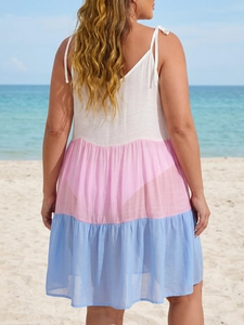 Back view of color-block tiered sun dress with adjustable bow straps at a sunny beach