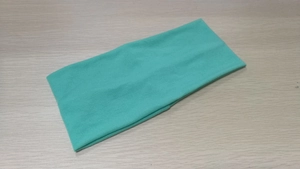 Close-up of mint green wide elastic headband showing soft knit fabric texture