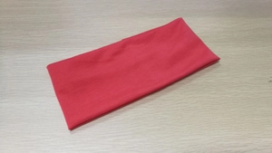 Detailed texture of a rose red elastic yoga headband on a light wood background