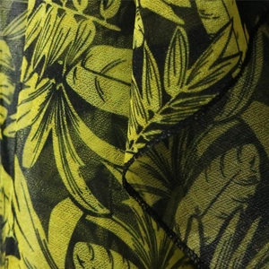Close-up of tropical leaf print fabric with detailed black stitching and soft texture
