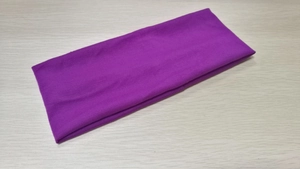 Detailed macro view of the solid purple elastic sports headband texture on wood