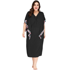 Détail du col en V avec lacets et franges à pompons colorés sur une robe caftan grande taille