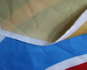 Macro detail of high-quality white edge stitching on multi-color striped beach towel