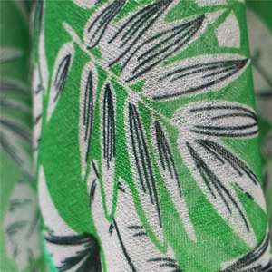 Macro detail of tropical leaf print on lightweight green fabric with fine fiber texture