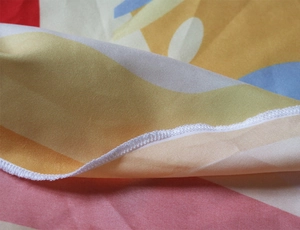 Close-up of durable white overlock stitching on colorful pizza print beach towel
