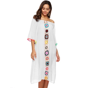 Détail de la broderie crochet colorée et pompons sur la robe de plage blanche